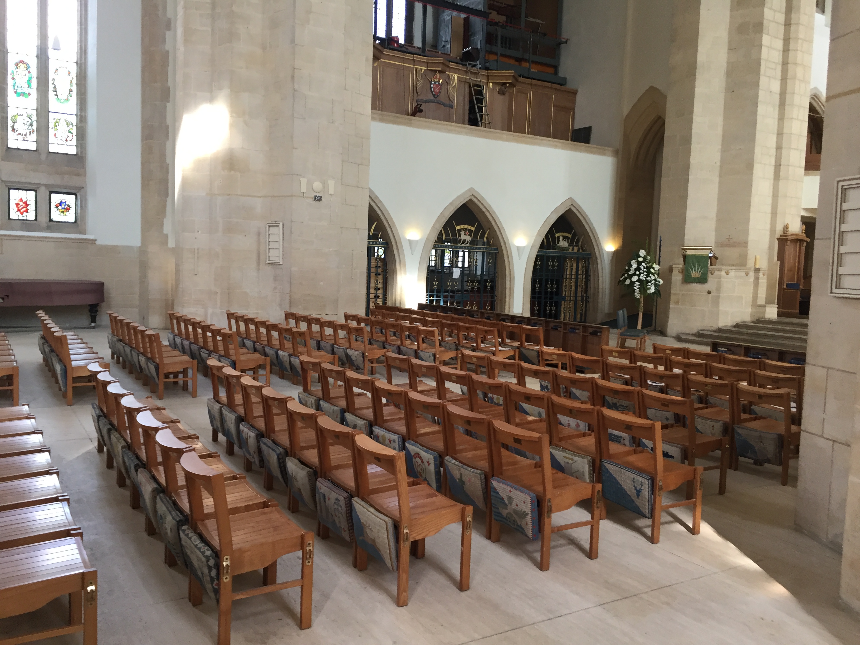 The interior of Guildford Cathedral, including rows of wooden chairs, and archways along the way that each curve to a point in the centre at the top.
