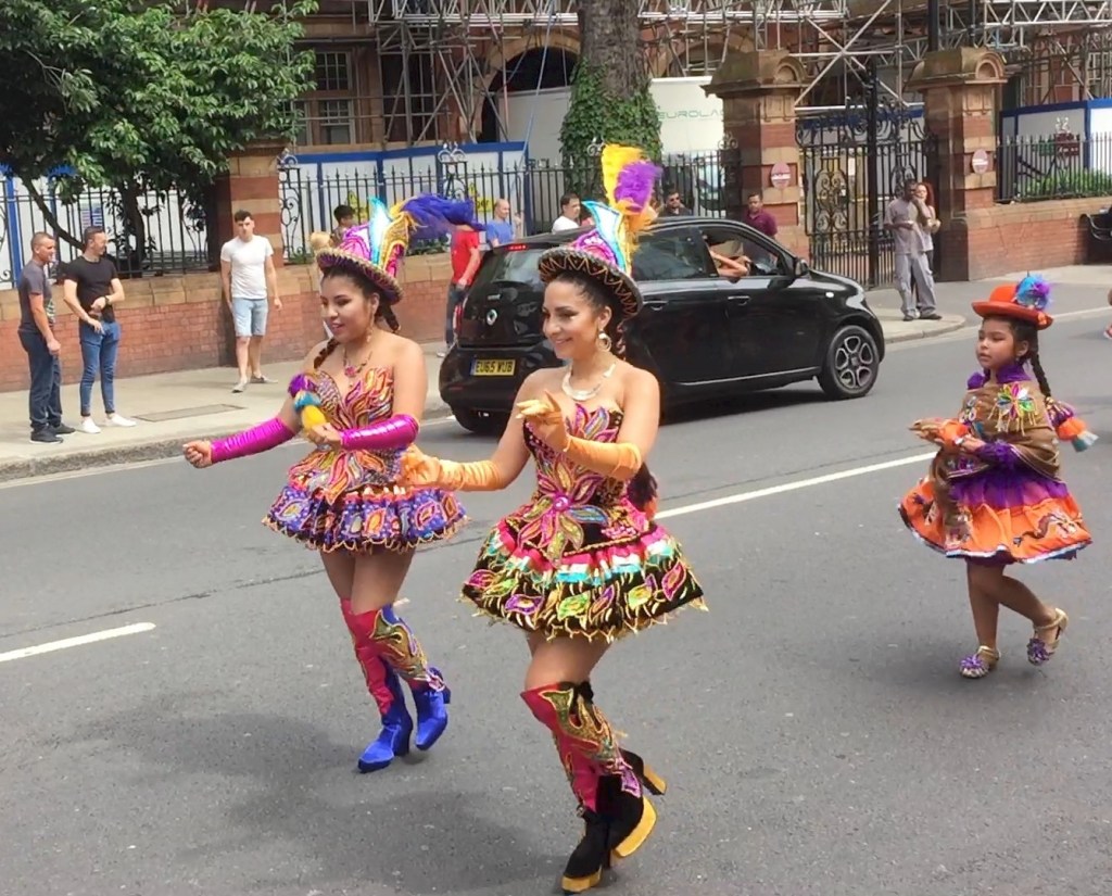 2 ladies and a young girl dancing in brightly coloured dresses and hats in the Newham Carnival.