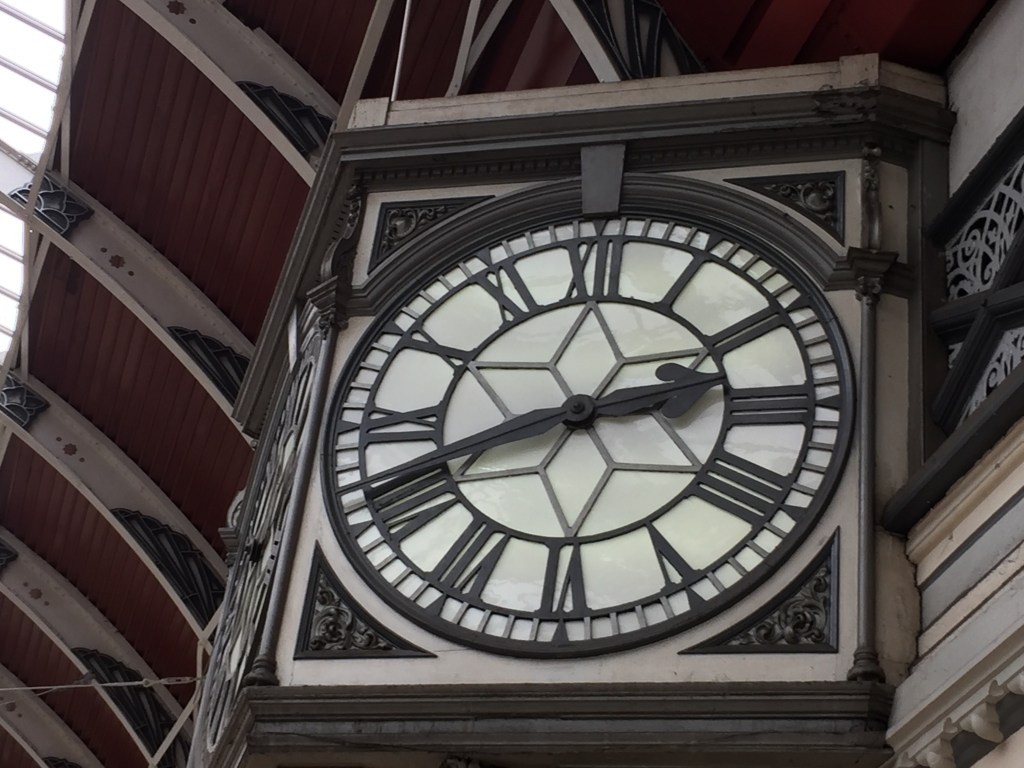 A white clock face with black Roman numerals, hands and edging, and a 6-pointed star in the centre.