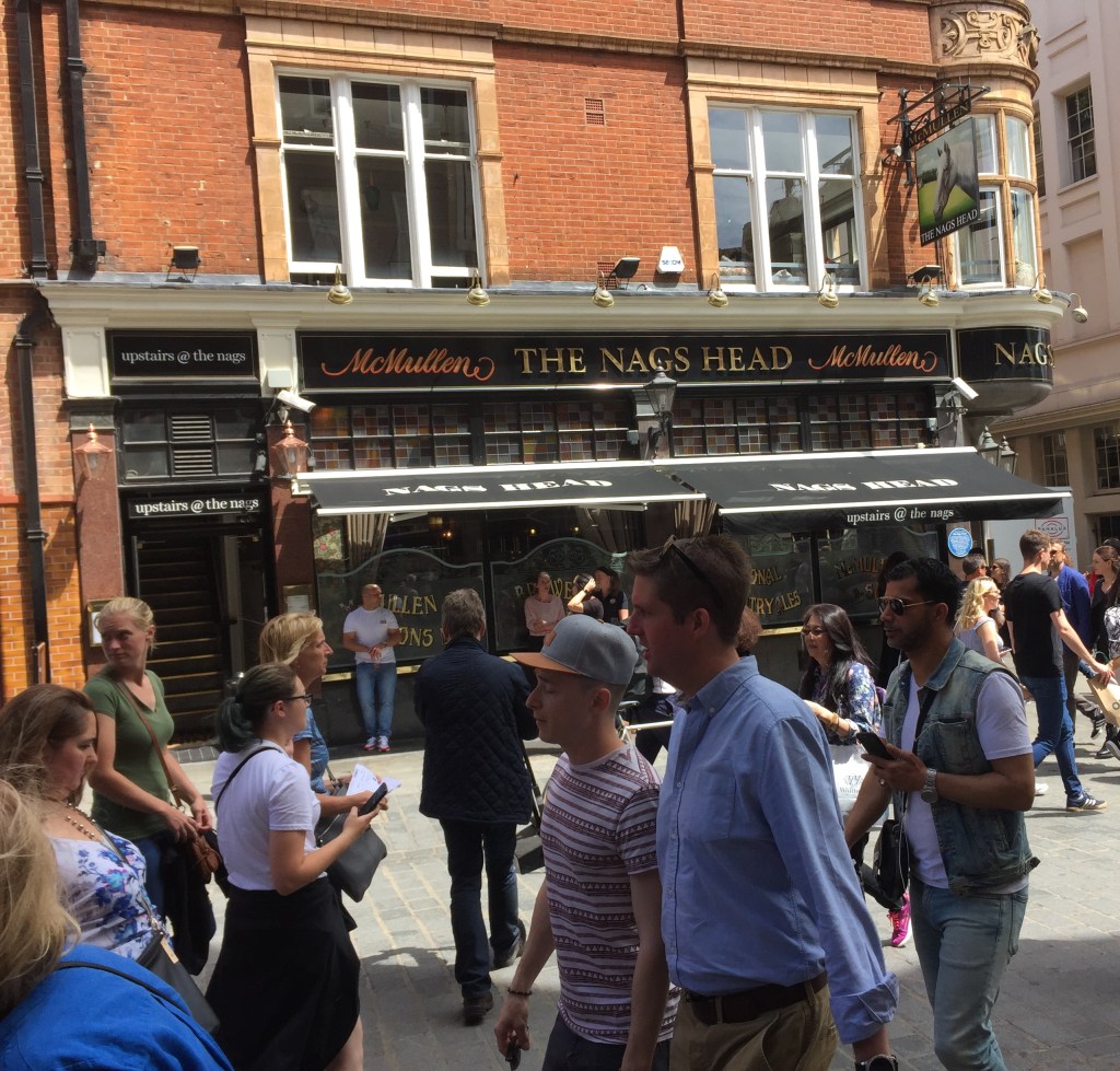 A pub, under the brand McMullen, called The Nag's Head, with a picture of a white horse on the pub sign hanging by one of the upper windows.