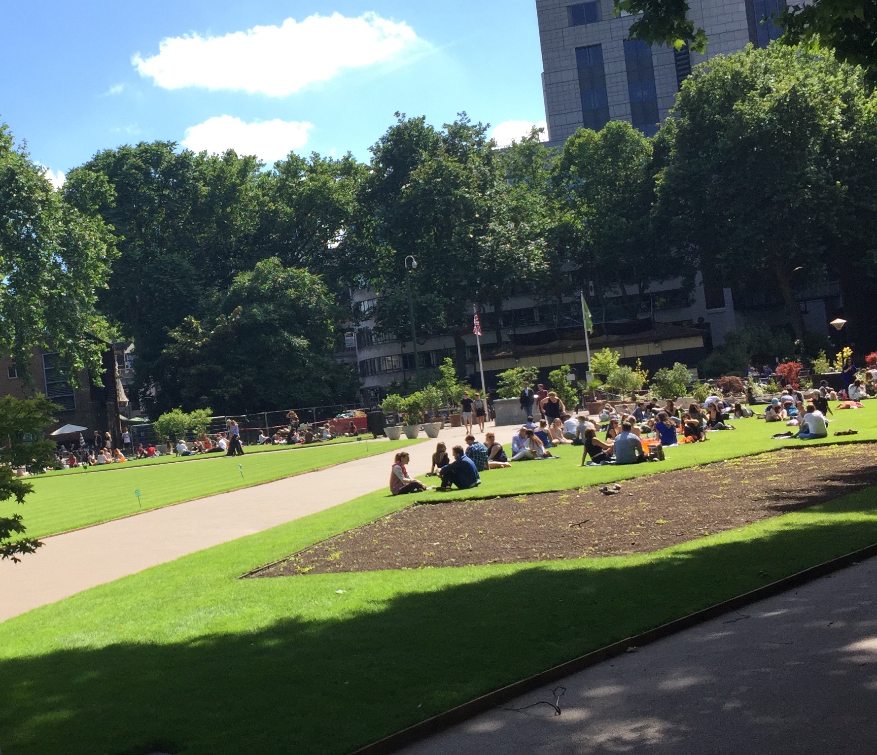 People sitting on the grass in the sunshine in Victoria Embankment Gardens.