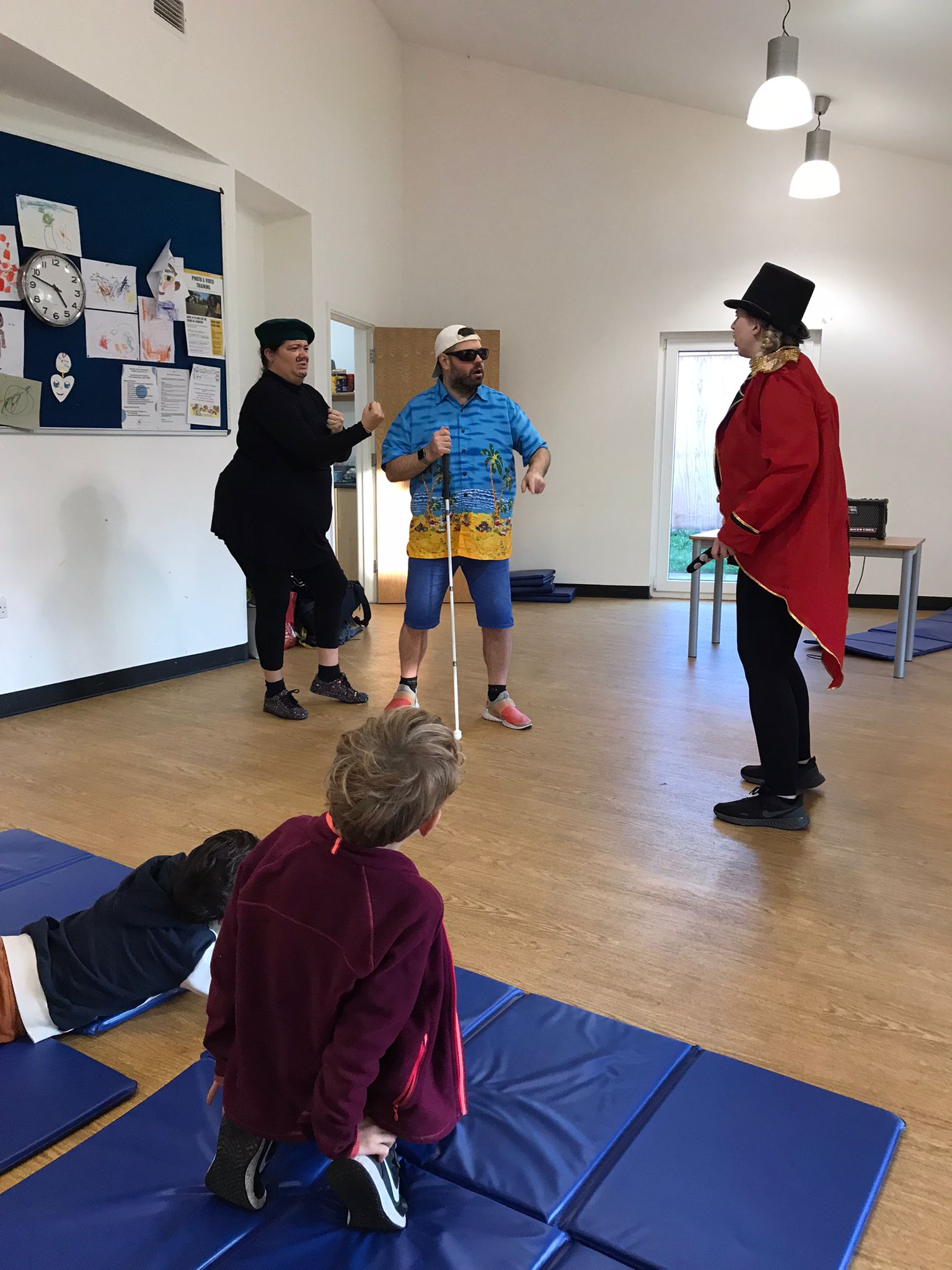 In the Super Power Panto rehearsal studio, Claude and Billy talk to Sir Sunblock. Claude is in a pose with his fists raised as if looking for a fight.