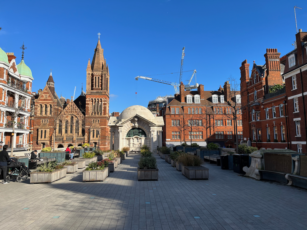 Brown Hart Gardens, a paved area with rows of square plant boxes in the centre, and benches along the sides. The garden is a raise area accessed by steps, so it's higher than the roads surrounding it.