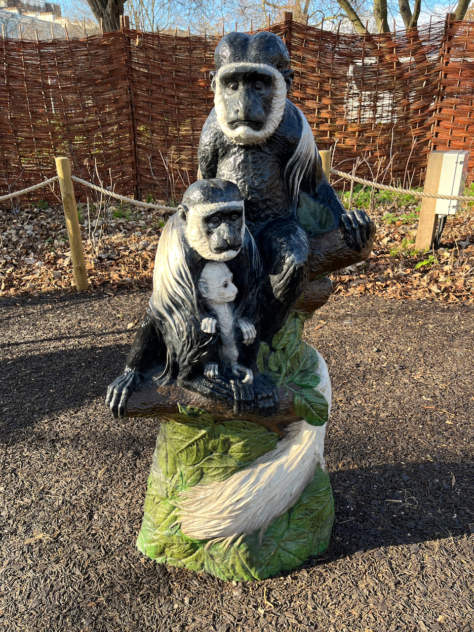A large statue of 3 colobus monkeys, consisting of a mother and father with black and white fur, and a baby that's totally white in its mother's arms.