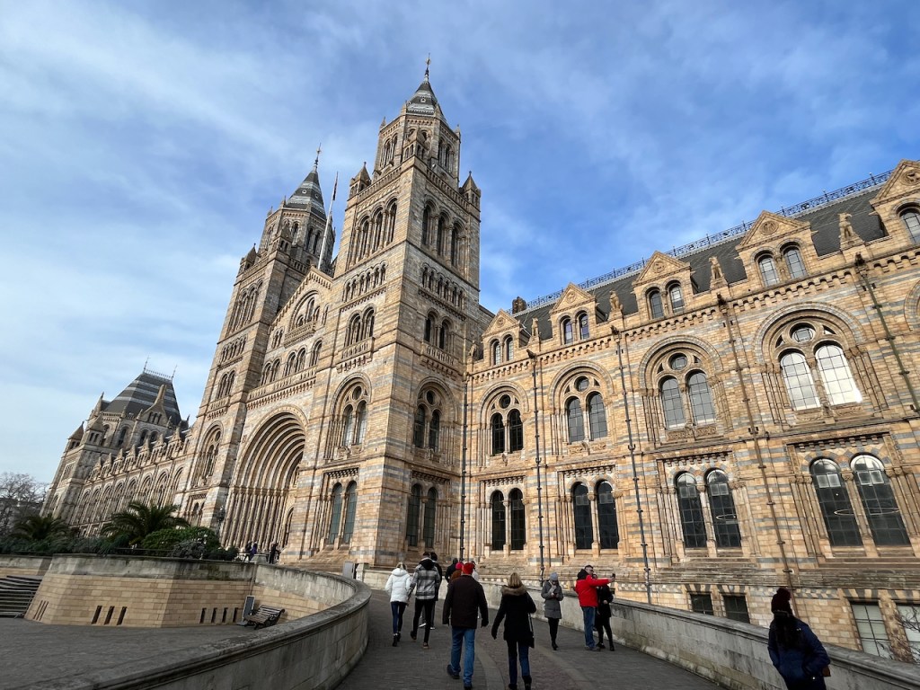 The huge Natural History Museum building, with its tall spire-topped towers either side of the arched entrance.