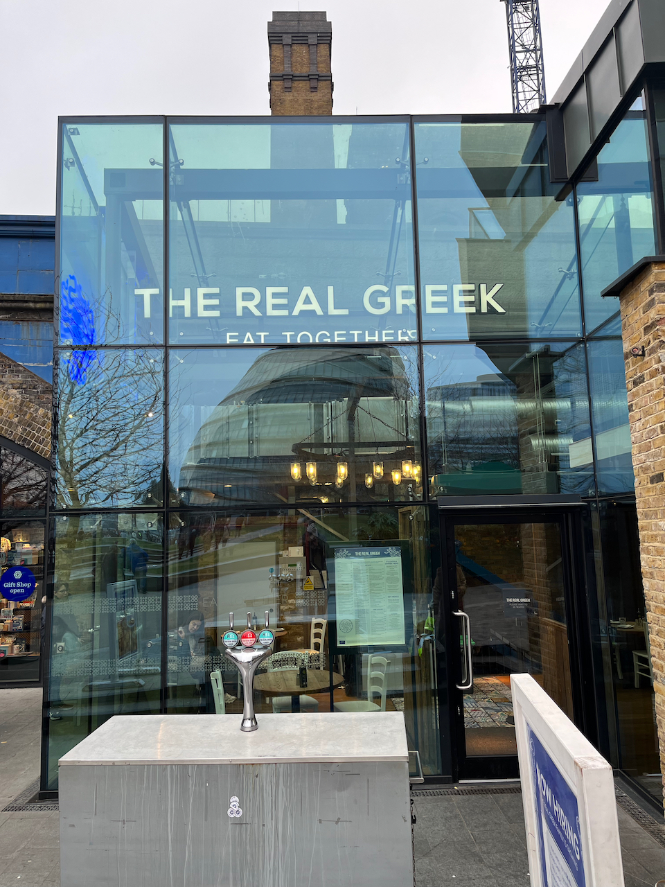The glass-fronted exterior of The Real Greek restaurant.