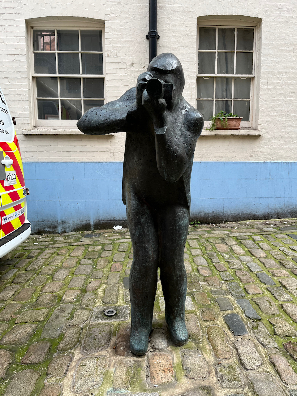 Bronze statue of fashion photographer Terence Donovan pointing his camera.