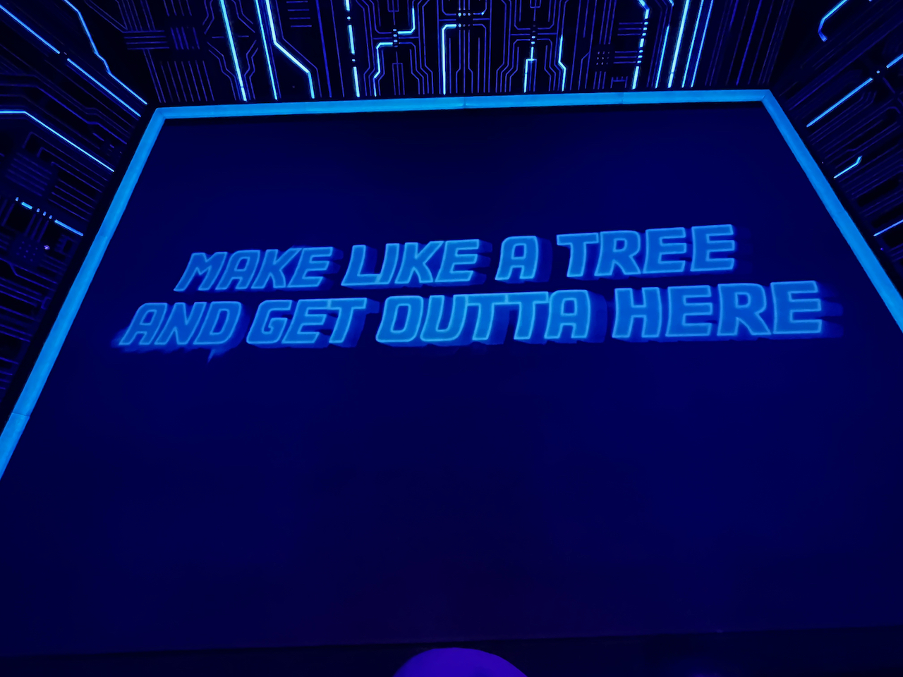 A message in large capital letters on the projection screen at the front of the stage for Back To The Future The Musical, which reads Make like a tree and get outta here.