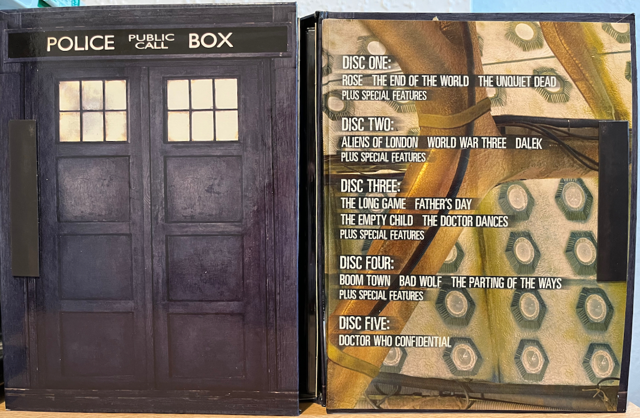 The open door flap of the Tardis-style box set for Doctor Who Series 1. The inside of the door flap lists the episodes on each of the 5 DVDs in the set.