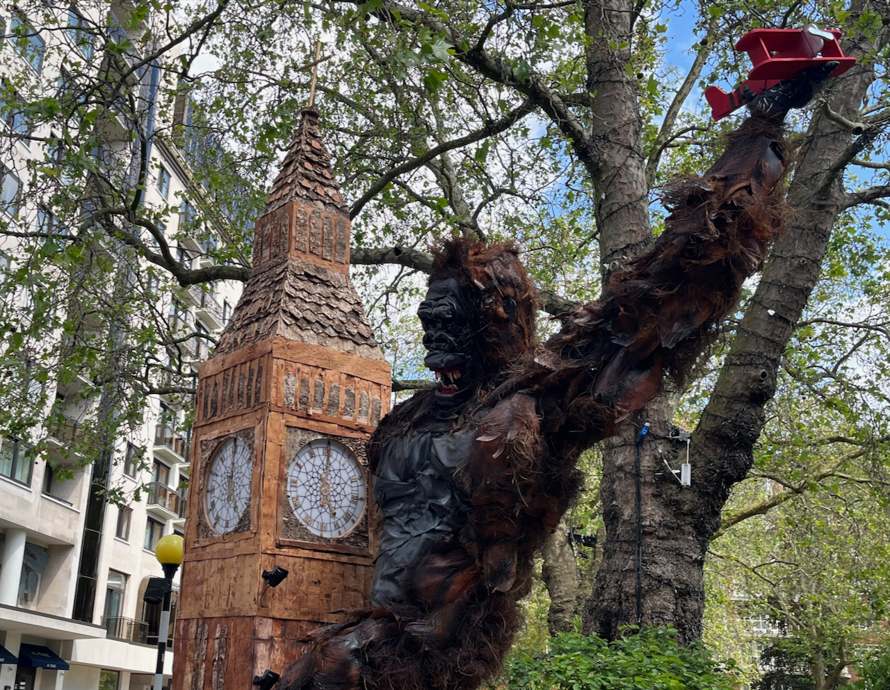 A close-up of the upper half of King Kong's floral display, where the giant black gorilla has his teeth bared while grasping on to Big Ben with one arm and holding up a small red bi-plane with the other hand.