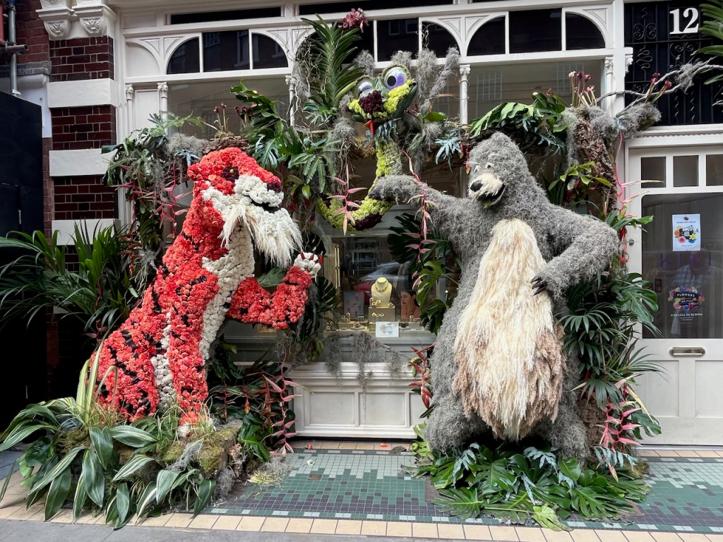 Floral display depicting The Jungle Book, with large models of Shere Khan the tiger, who has a red and black striped body and a white chest, and Baloo the bear, who has a grey body and a white chest.