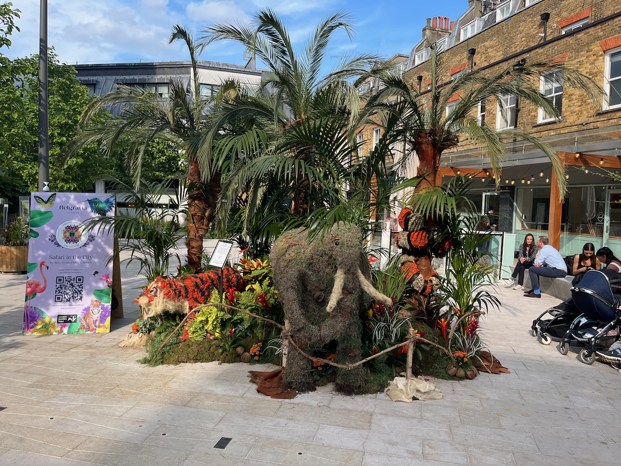 Floral installation of a safari scene, including a grey elephant with big white tusks, an orange and red striped tiger, and some tall leafy trees.