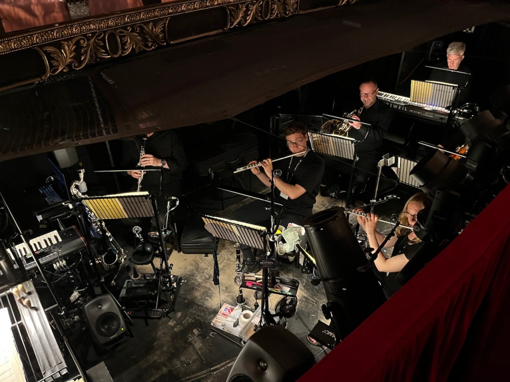 The right side of the orchestra pit at Phantom Of The Opera, with people playing wind instruments and a keyboard.