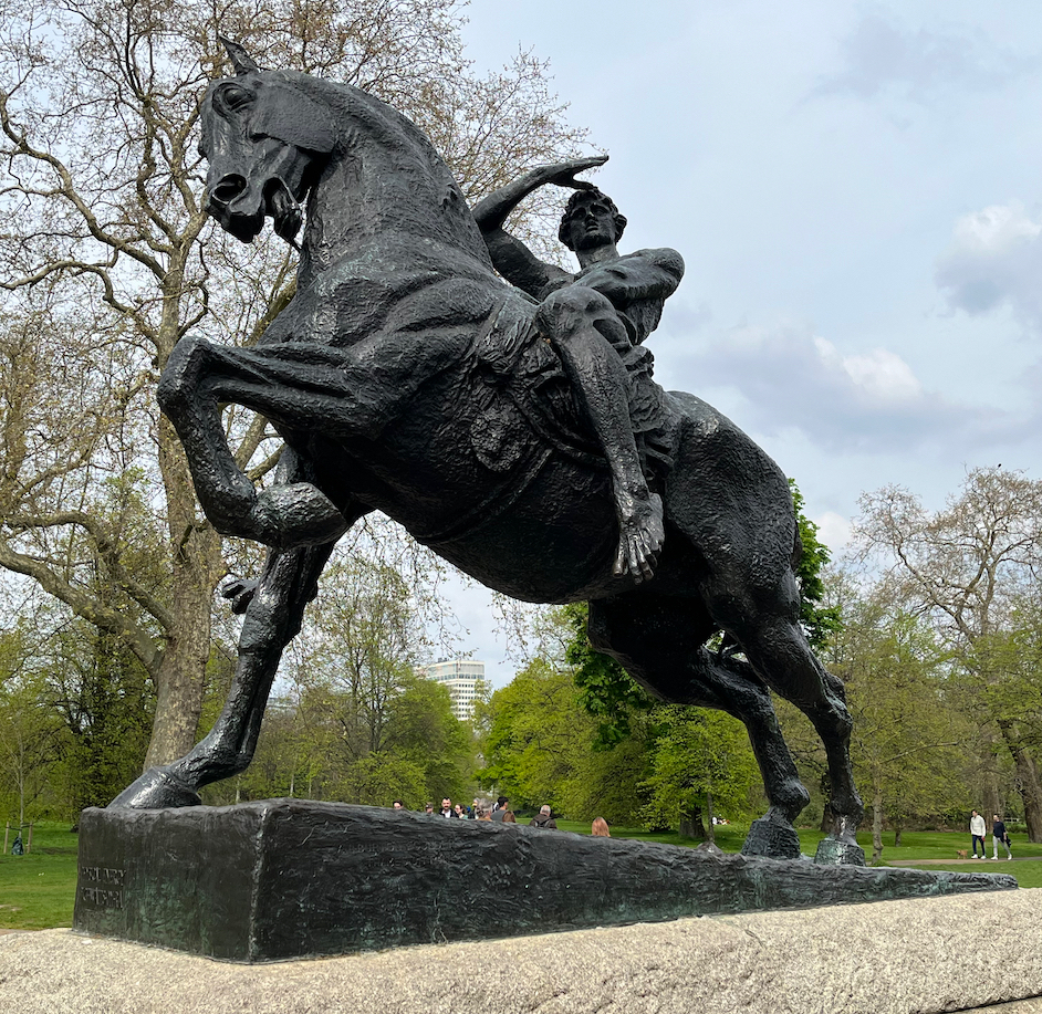 The Physical Energy Statue, showing a man riding a horse. The man has his hand raised up to his forehead, as if shielding his eyes from the sun as he looks ahead, while the horse has its left front leg raised and its mouth open, as if in mid-gallop.