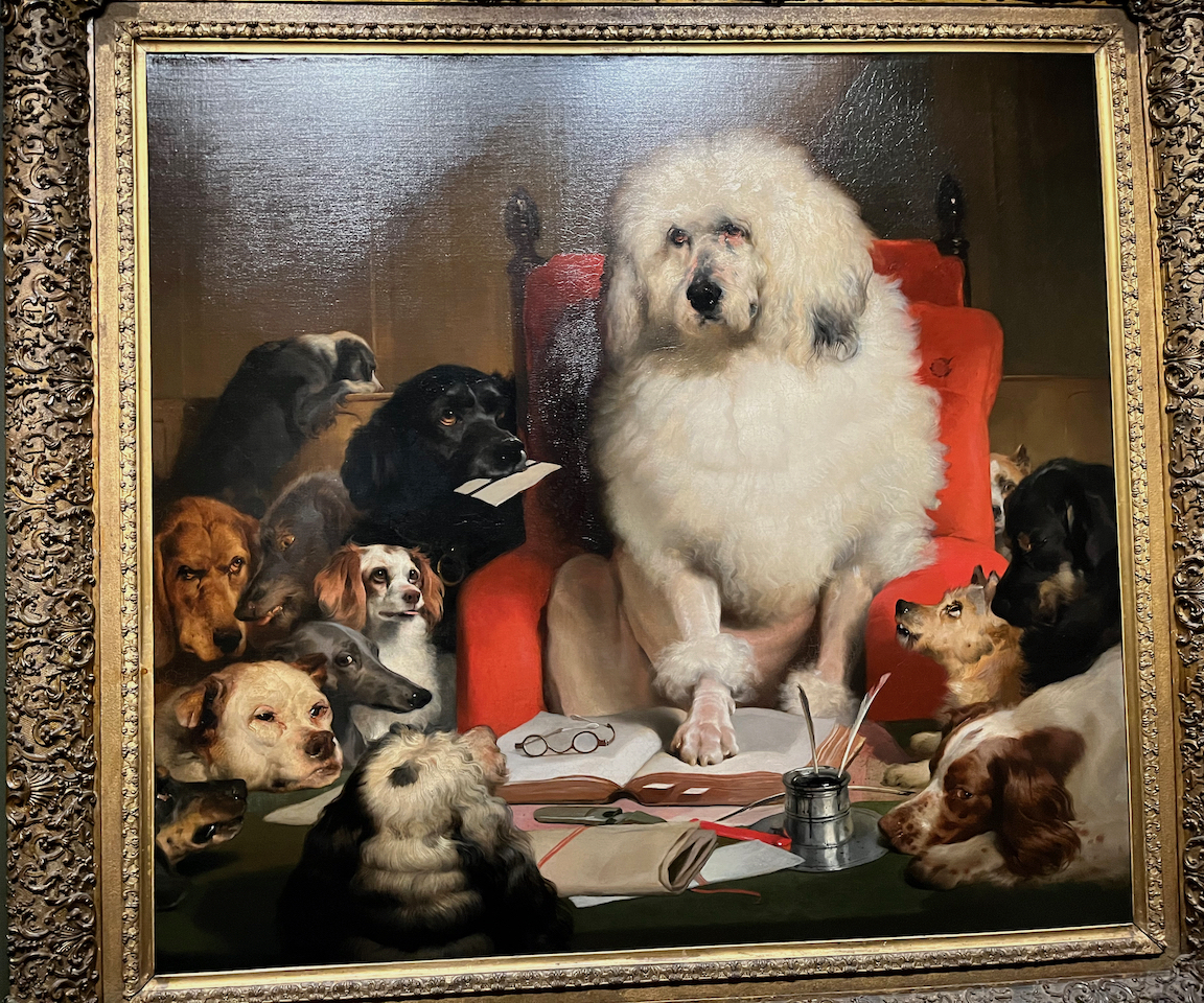 A painting showing a big white fluffy dog standing with his paw on the left page of an open book, while a pair of glasses sits on the right page. A black dog next to it is holding a piece of paper in its mouth, as if wanting to present it to the white dog. Other dogs of various breeds are gathered around, as if waiting for the big white dog to speak to them.