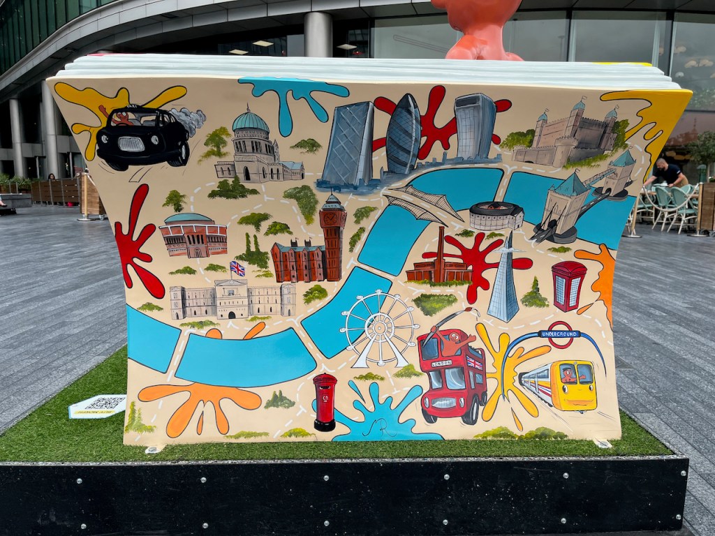 The back of the bench sculpture called Morph Over, There's Room For Two. The back of the bench depicts a painted map of London, with lots of iconic sights drawn on, including a black cab, a red double decker bus, a red postbox, a red phone box, a Tube train, the Royal Albert Hall, Buckingham Palace, St Paul's Cathedral, the Houses of Parliament, Big Ben, the Gherkin, the Walkie Talkie Building, the Tower of London, Tower Bridge, The Shard, Shakespeare's Globe, the Tate Modern and the London Eye.