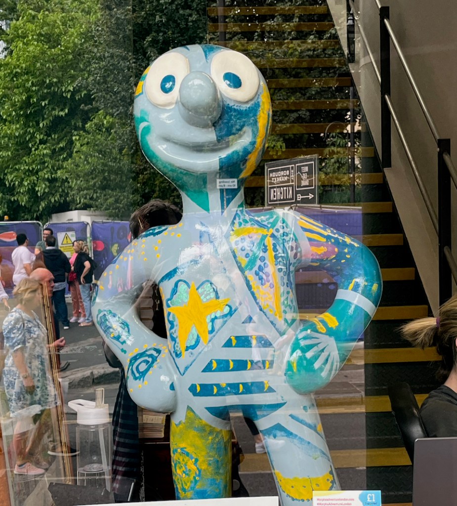A small statue of Morph called Neville. His light blue body is designed to look like the ocean, with children's drawings of starfish, other marine wildlife and coral.