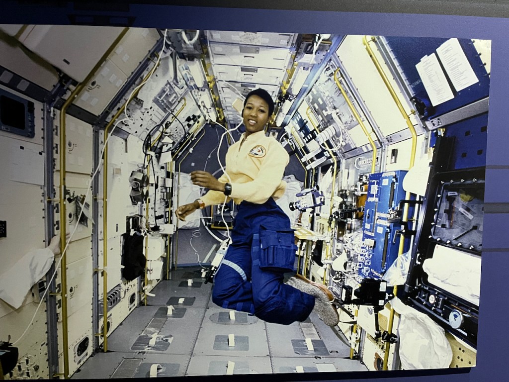 Mission Specialist Mae Jemison, the first woman of colour in space, wearing a yellow shirt and blue trousers while floating inside the Space Shuttle Endeavour.
