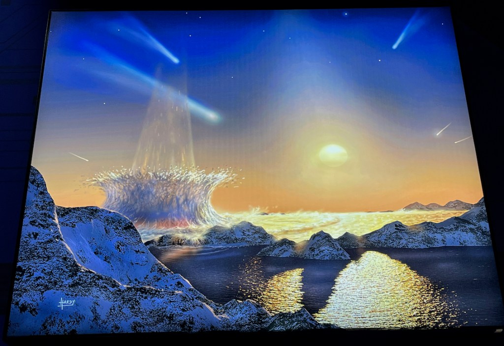 Artwork called Tau Ceti by David A Hardy, showing asteroids smashing into the sea next to rocks beneath a sunny sky.