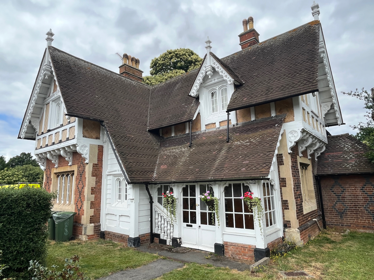 Blackheath Gate Lodge, a Victorian building with Tudor stylings, mainly white but with some light brown elements, and very deep sloping roofs.