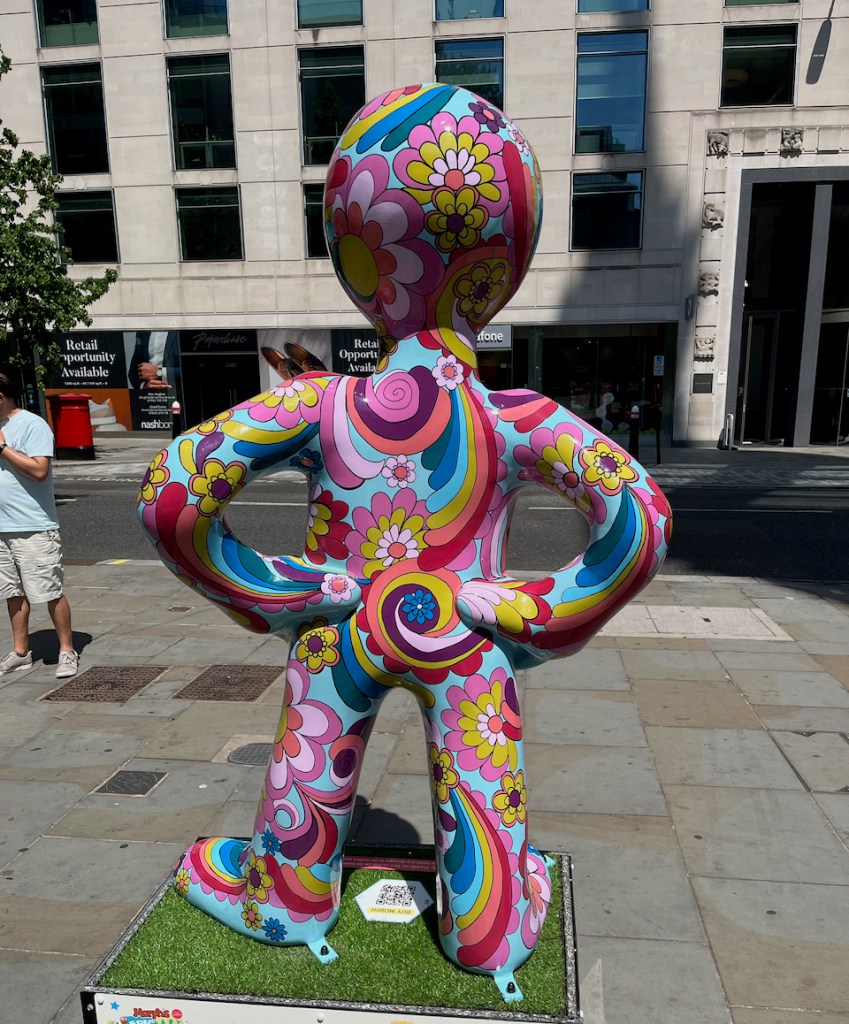 The back of Good Vibes, a statue of Morph covered in a colourful psychedelic mixture of swirling rainbows, flowers and other patterns.