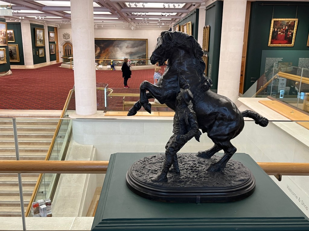 A small statue of a horse rearing up on its hind legs as a man stands next to it holding on to the reins.