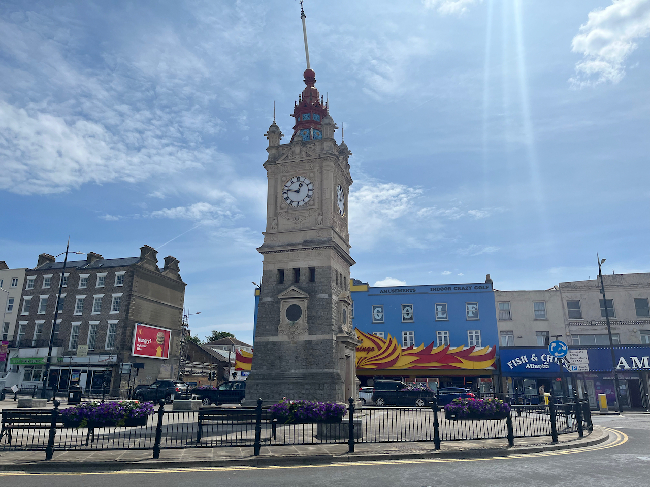 A stone clock tower in the middle of a small roundabout in Margate.