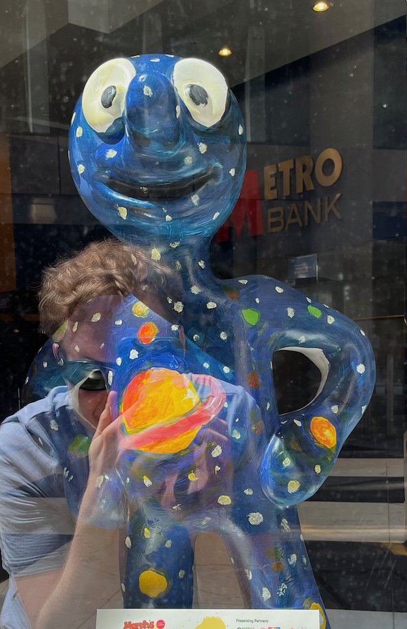 Near and Far, a dark blue statue of Morph covered in children's drawings of stars and colourful planets.