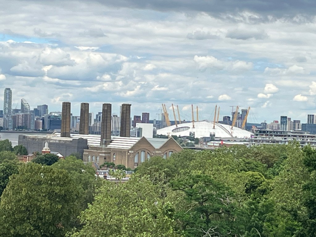 A view across trees to the large white dome that is the O2 Arena in the distance.