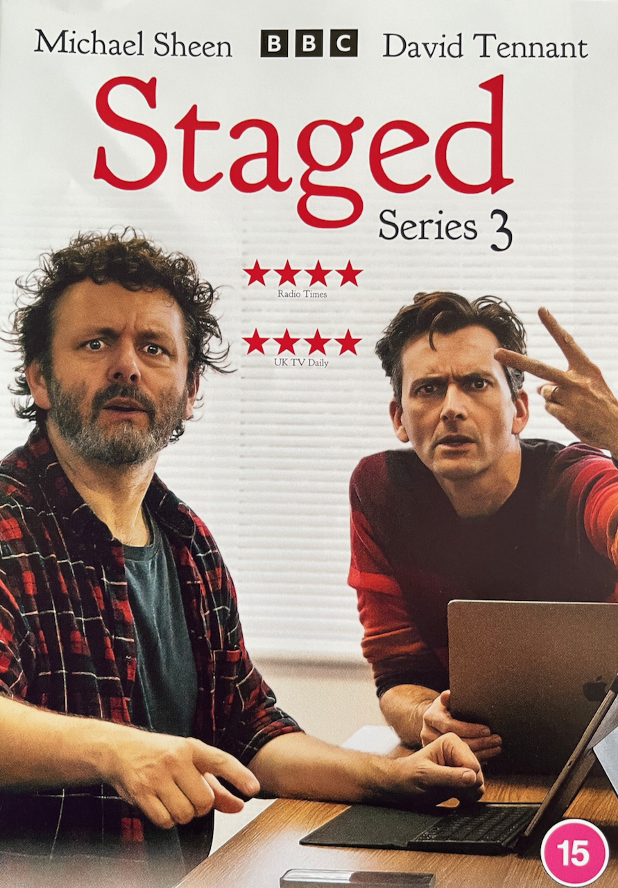 Front cover of the DVD for Series 3 of Staged, showing Michael Sheen and David Tennant sitting together at a table, each with a laptop in front of them. Both are looking at the camera, and David is giving the V-sign.