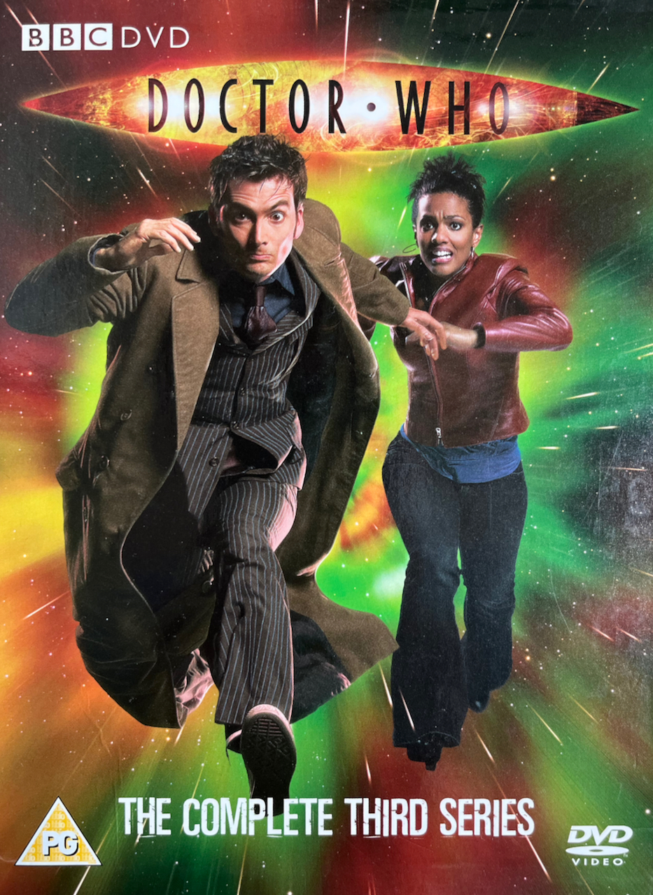 Cover art from the old Doctor Who Series 3 DVD set, featuring David Tennant's Doctor wearing a brown jacket over a pinstripe suit, running with a determined look on his face. Martha Jones, in a red leather jacket and black trousers, clings on to his left arm as she runs alongside him with a look of terror on her face.
