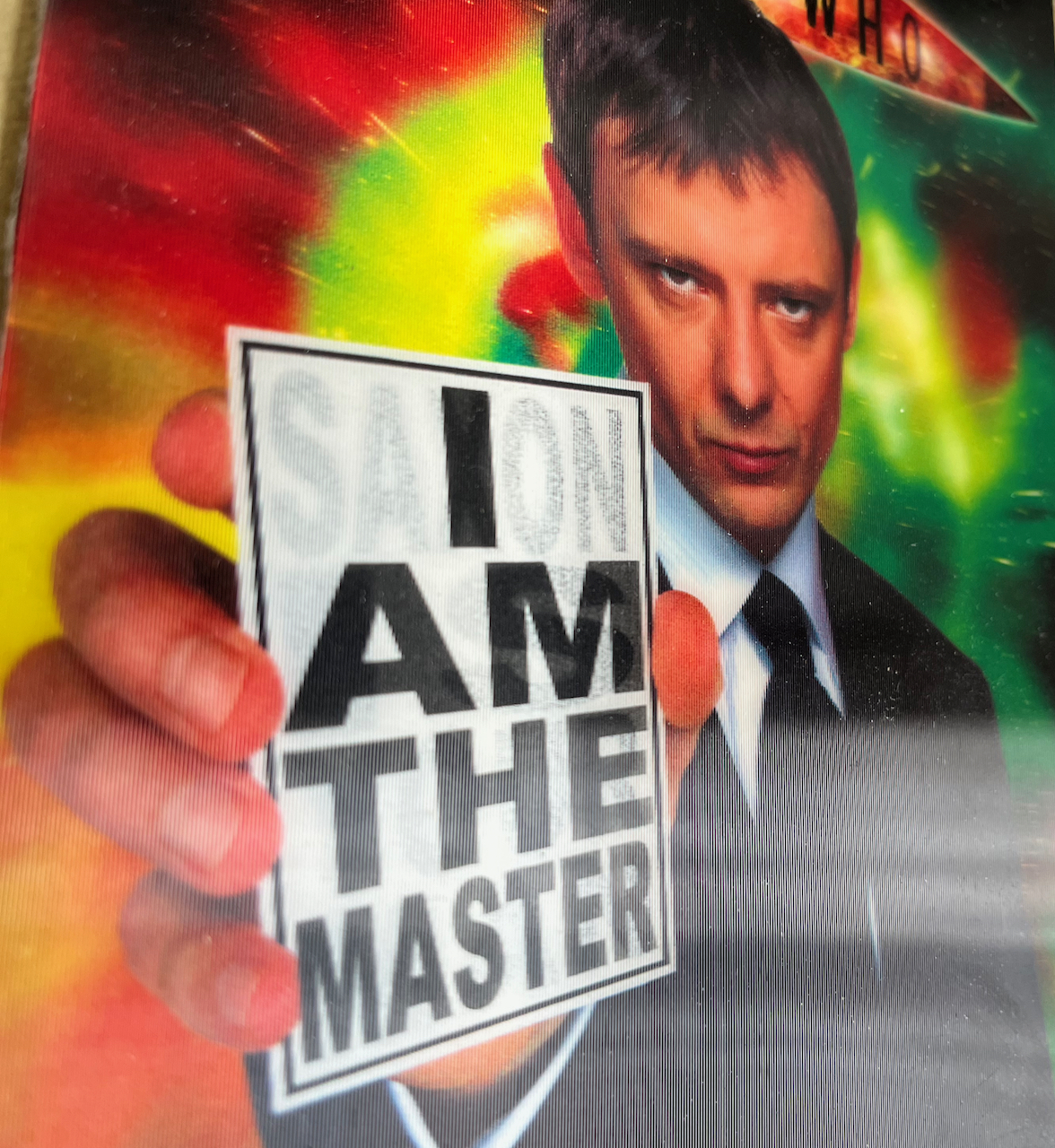 Lenticular cover art from the old Doctor Who Series 3 DVD set, featuring John Simm as The Master holding up a piece of white card with large black lettering that reads I Am The Master. In fainter black lettering behind it are the words Saxon Is Your Man, which can be seen when tilting the case to a different angle.
