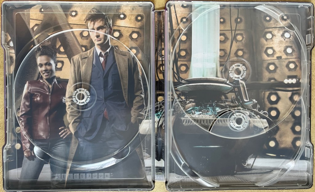 The interior spread of the Doctor Who Series 3 Blu-ray steelbook, behind where the discs are stored, showing a photo inside the Tardis, with David Tennant's Doctor and Martha posing together on the left, and the round console on the right.