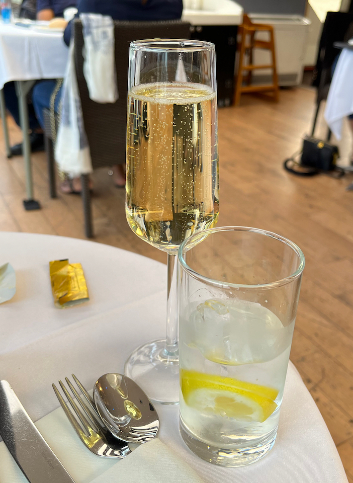 A flute of champagne and a glass of water, on a table covered in a white tablecloth, on the Millennium of London boat.