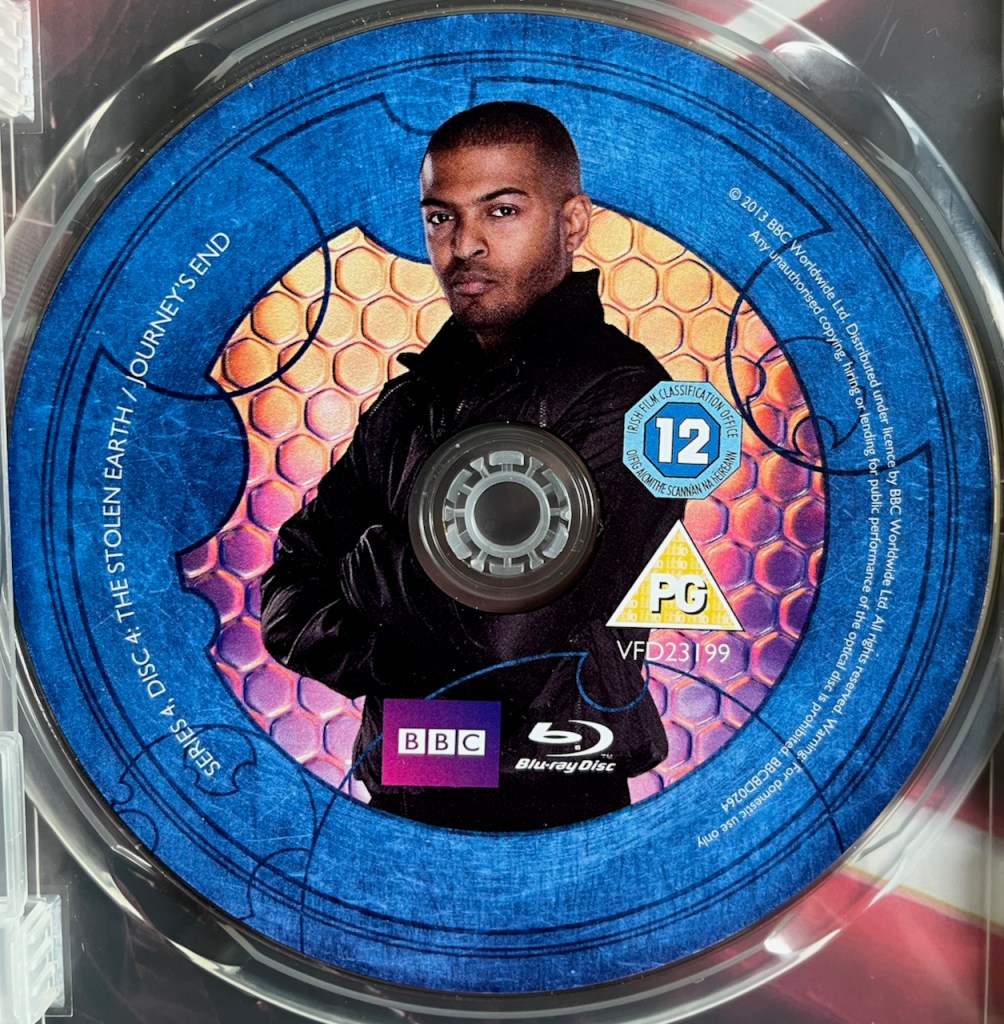 Disc 4 in the Doctor Who Series 4 Blu-ray set, featuring a photo of Mickey Smith in a black leather jacket, looking stern with his arms folded. A blue border around the edge of the disc contains the episode names and copyright information.