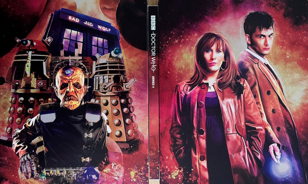 The full cover spread artwork for the Doctor Who Series 4 Blu-ray steelbook. The front cover shows David Tennant as the Doctor, looking sideways on at us, wearing a long brown coat with his sonic screwdriver pointing downwards in his right hand. Donna Noble, his redheaded companion, is in front of him, looking straight ahead at us, wearing a shiny red jacket over a dark blue top. Meanwhile the back cover shows Davros and a couple of Daleks in front of the Tardis, with a few large planets in the sky in the background.