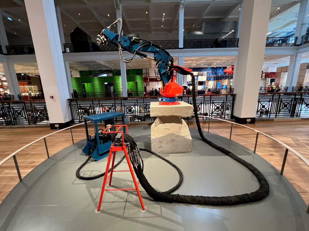 James Capper's Atlas Prototype. This is a large hydraulic arm, with a round drill head at the end, on a big stone pedestal. The arm is able to turn all the way around, and bend downwards enough to drill away at its own pedestal, which it has been doing for some time, leaving a wide chasm around the centre of it.