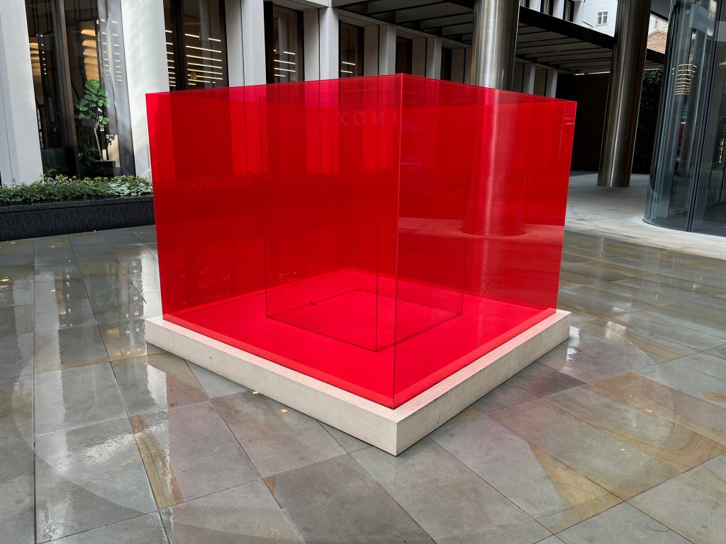 A sculpture called Pacific Red 4 by Larry Bell, consisting of a large red transparent box with another transparent box nested inside it.
