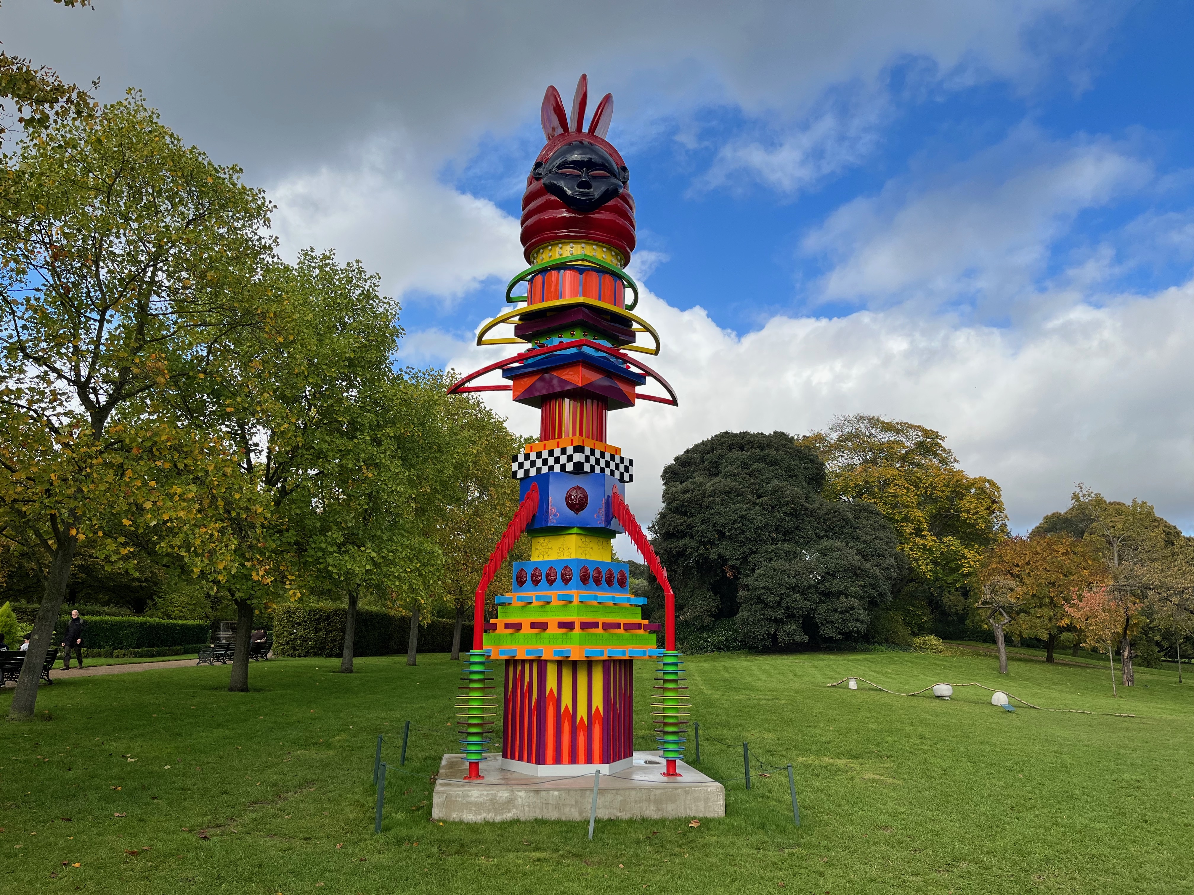 A sculpture by Zak Ové called The Mothership Connection. It is a large, brightly coloured and decorated totem pole, designed to look a little bit like a rocket ship. At the top is a black face with rabbit-like pointed ears.
