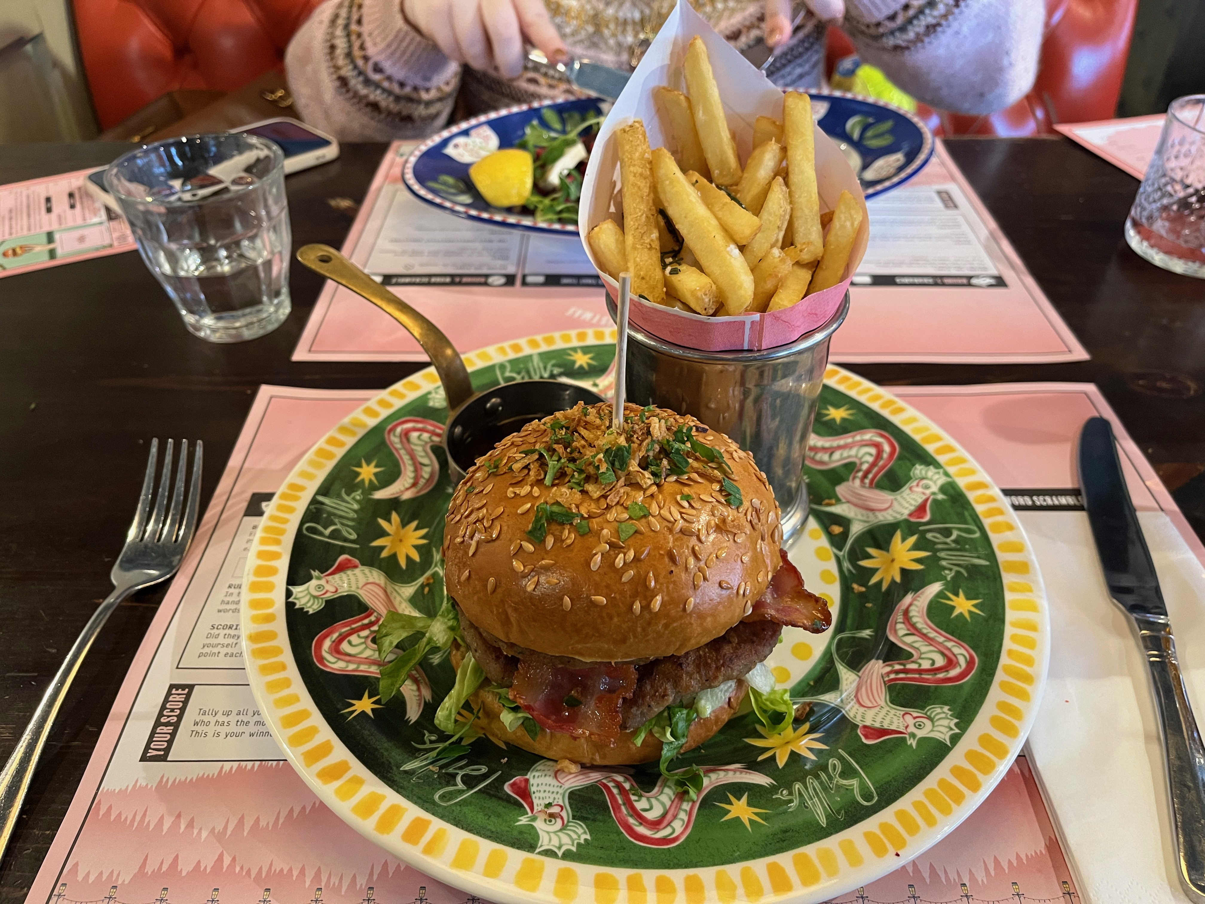 The Notorious Pigs In Blankets Burger at Bill's, consisting of a double pork patty, double smoked bacon, sage & onion mayo & cranberry sauce, with truffle gravy dip & crispy fried onions, accompanied by a pot of rosemary salted fries.