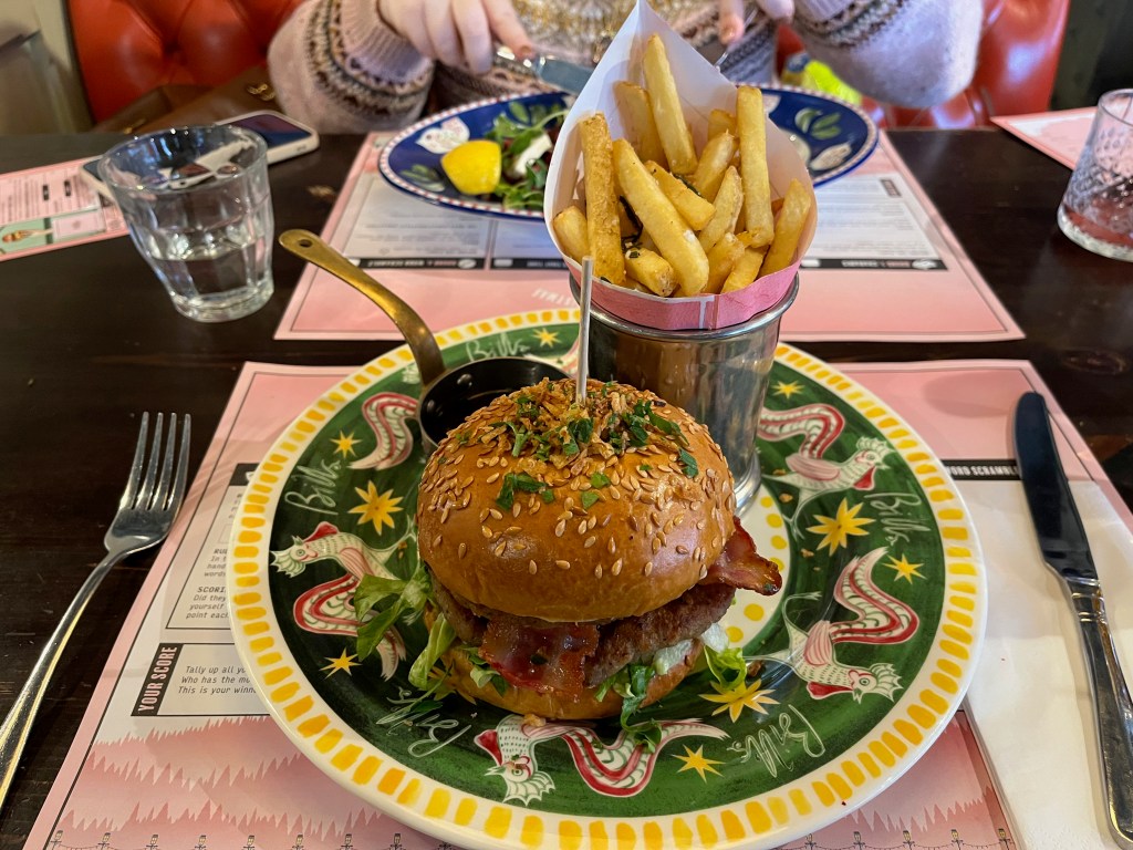 The Notorious Pigs In Blankets Burger at Bill's, consisting of a double pork patty, double smoked bacon, sage & onion mayo & cranberry sauce, with truffle gravy dip & crispy fried onions, accompanied by a pot of rosemary salted fries.