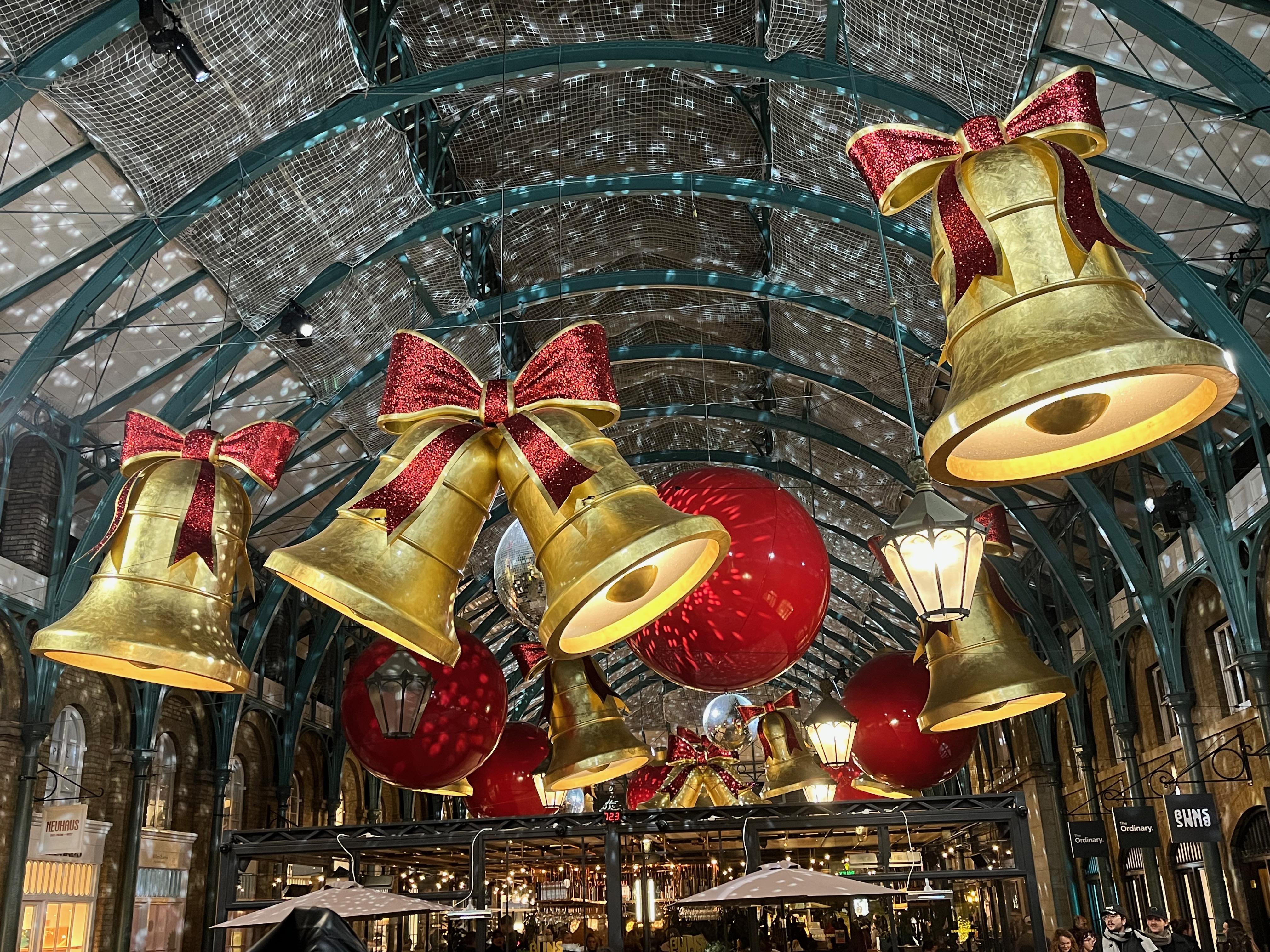 Large golden bells with red bows, big red baubles, spinning mirror balls and lamps hanging from the ceiling in Covent Garden Market.