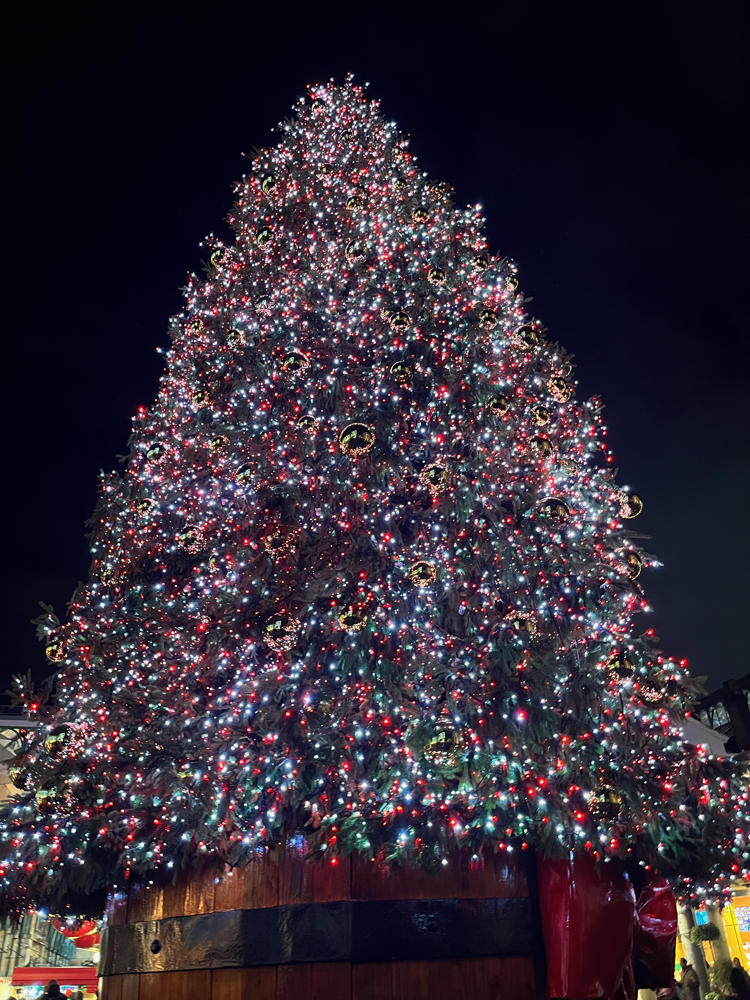 Close-up view of the huge Christmas tree in Covent Garden, covered in lights and big reflective baubles.