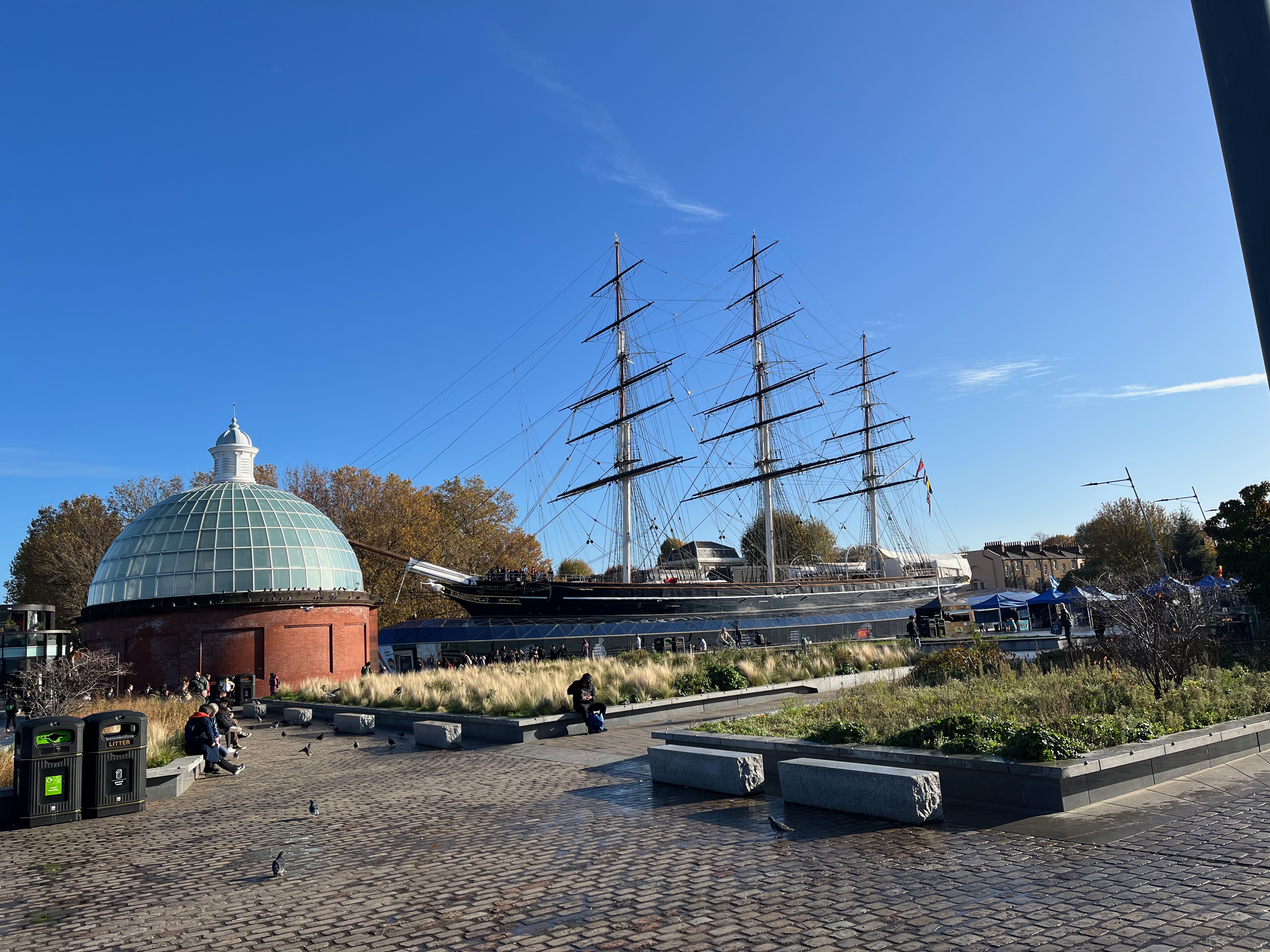 The Cutty Sark, next to the round building with a domed roof that forms the entrance to the Greenwich Foot Tunnel beneath the Thames.