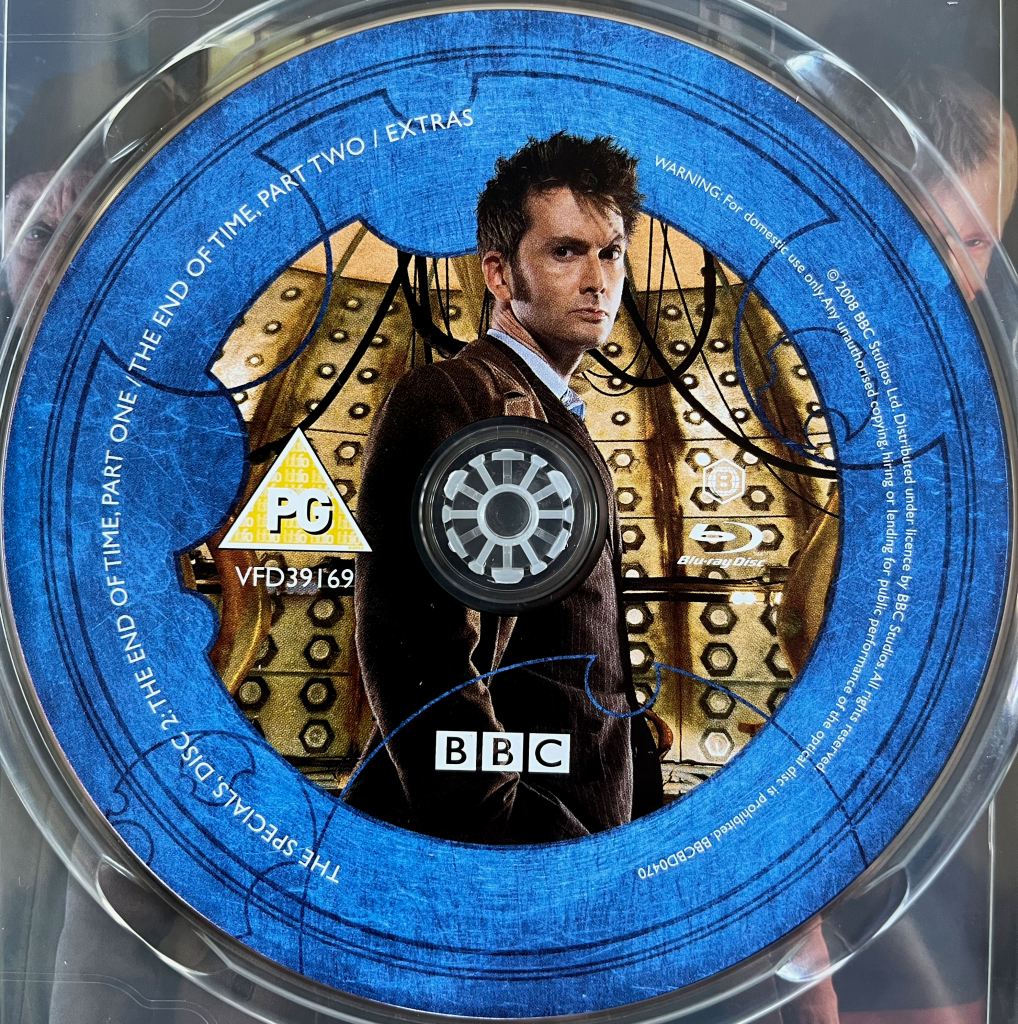 Disc 2 in the Doctor Who 2008 to 2010 Specials Blu-ray set. It features a photo of David Tennant as the Doctor in a pinstripe suit, standing inside the Tardis. A blue border around the edge of the disc contains the episode names and copyright information.
