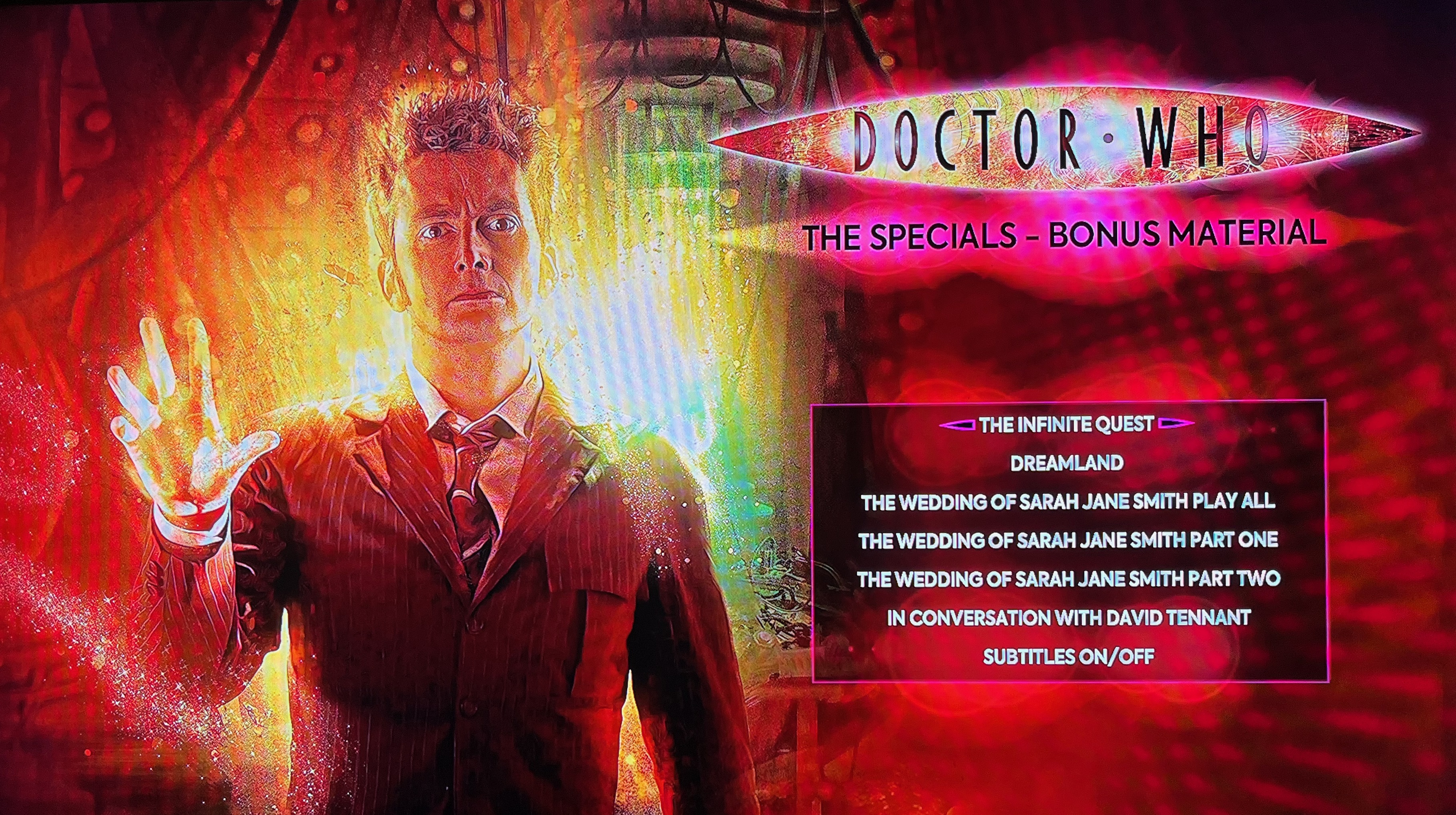 The menu for Disc 4 of the Doctor Who 2008 to 2010 specials Blu-ray steelbook, showing the various options below the Doctor Who logo on the right hand side, while to the left is an image of David Tennant's Doctor as he starts to regenerate.