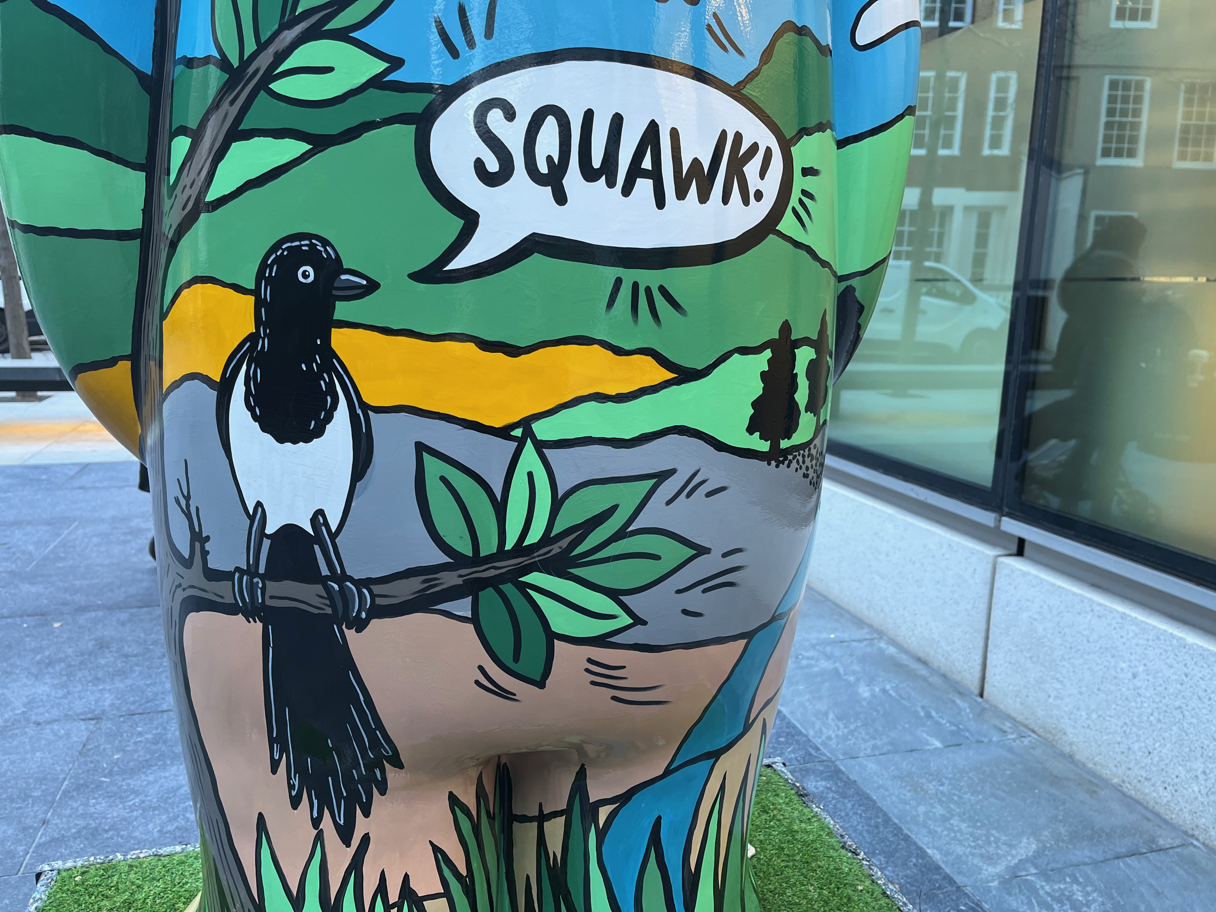Close-up of a sculpture of The Snowman called Four Calling Birds, showing a black and white bird going Squawk as it sits on a tree branch.