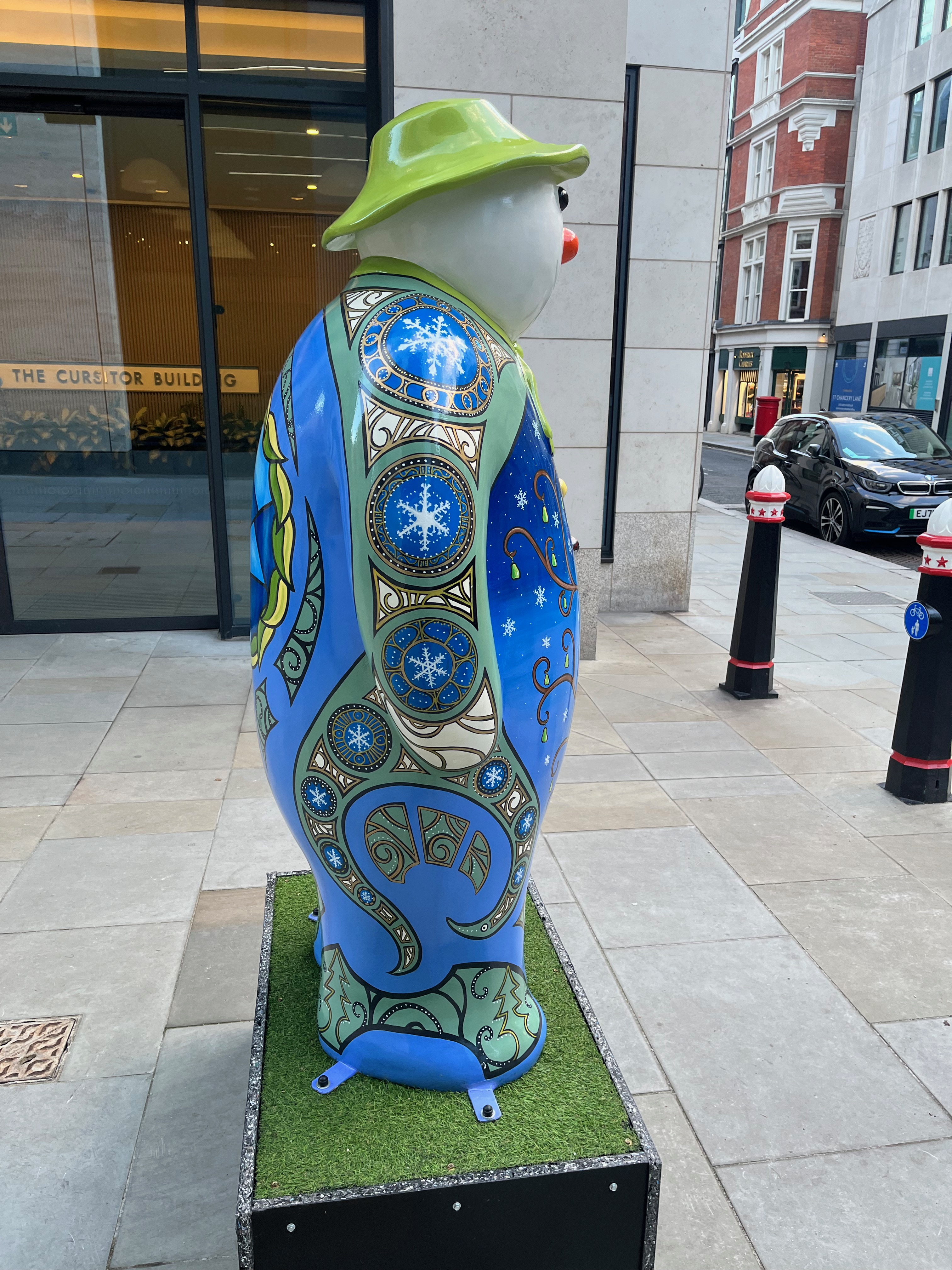 Side view of The Snowman statue called Partridge In A Pear Tree, with snowflakes contained within ornate circular frames on his arm and leg.