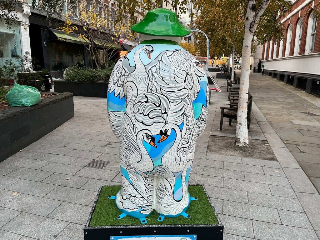 Back of the sculpture of The Snowman called Seven Swans a-Swimming, with one large swan spreading its wings at the top, and two swans facing each other lower down, forming a heart shape with their heads and necks.