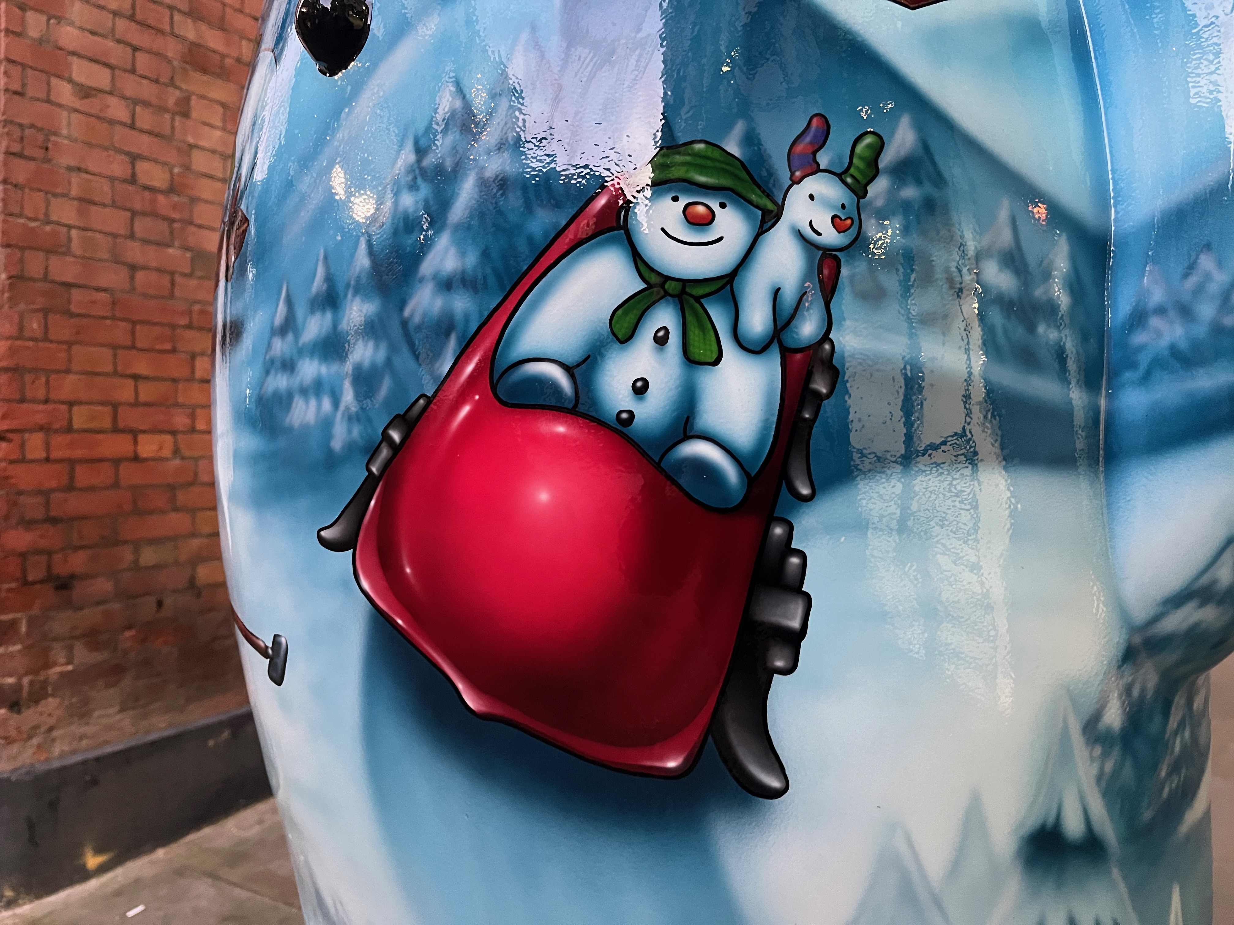 Close-up of the Ten Lords a-Leaping sculpture of the Snowman, showing the character riding in a big red sleigh, with the Snowdog on his shoulder.